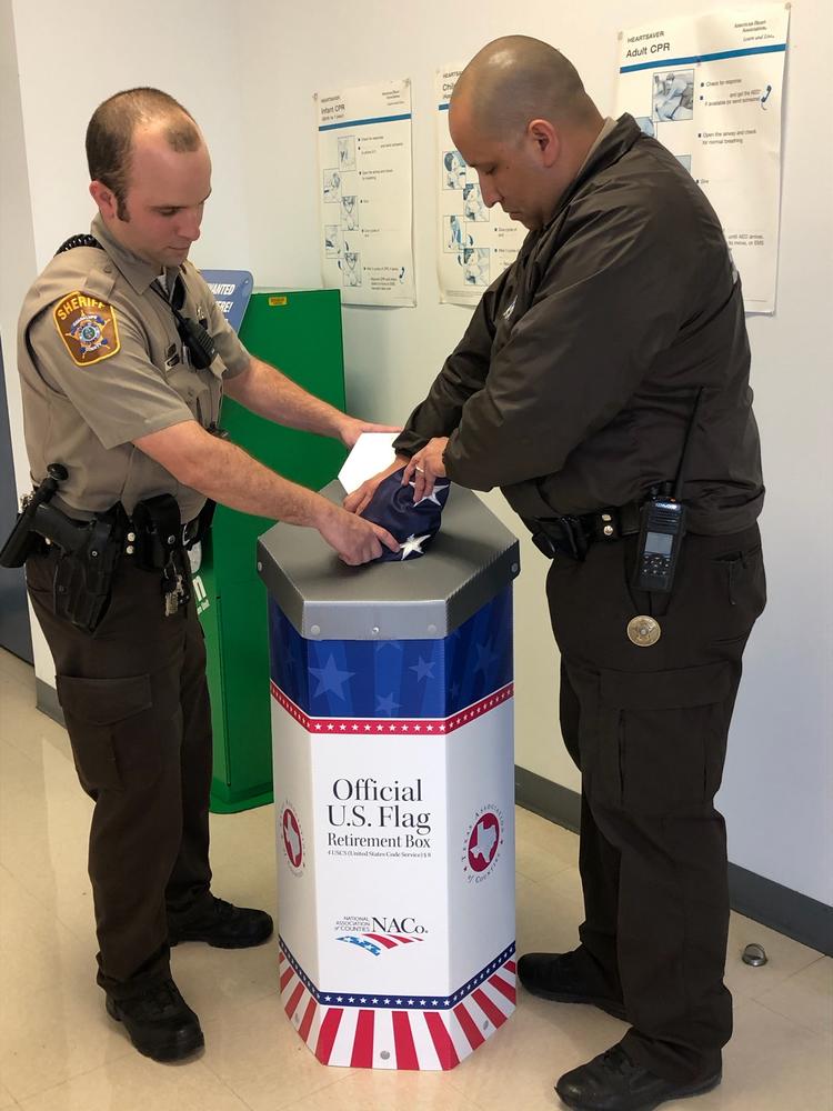 photo of two deputies placing flag in box