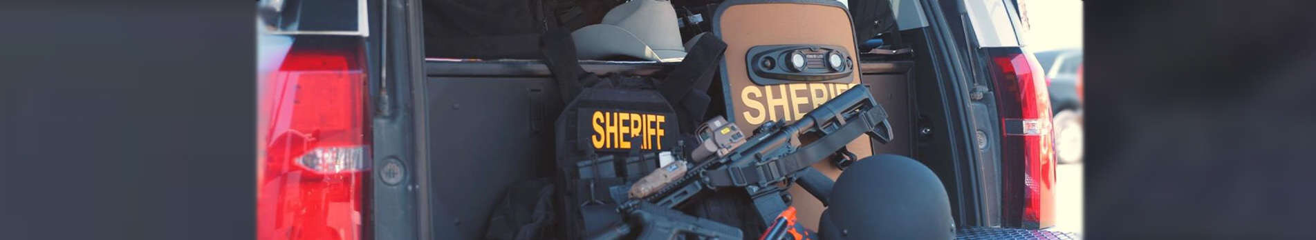 Sheriff riot gear and weapon in the back of a sheriff vehicle.